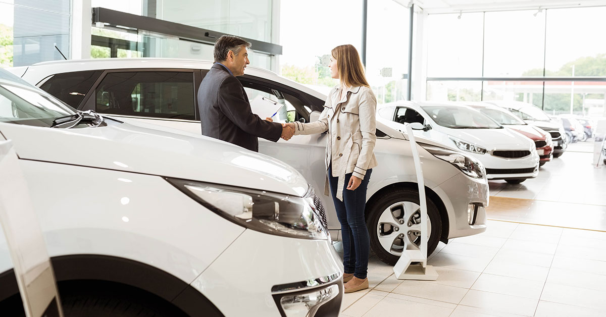 Woman shaking hands with a new car salesmen in the showroom.