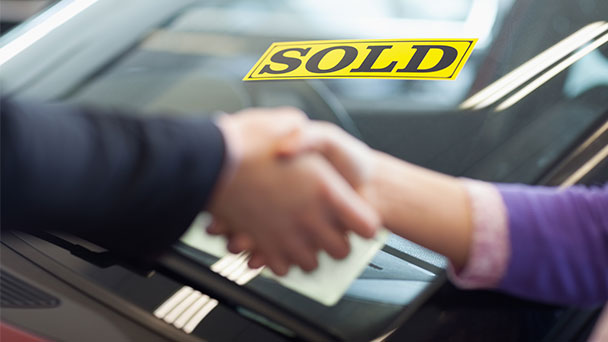 Buyer and seller shaking hands after selling the car.